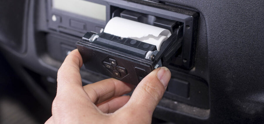 Digital tachograph with an open printer and visible roll of paper. Paper roll Replacement in a truck digital tachograph.