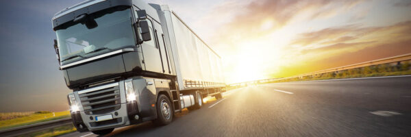 European truck on motorway with beautiful sunset sky and dramatic clouds. Transportation and cargo theme, free space for text.